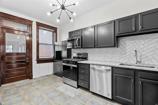 kitchen featuring tasteful backsplash, light stone countertops, appliances with stainless steel finishes, and sink