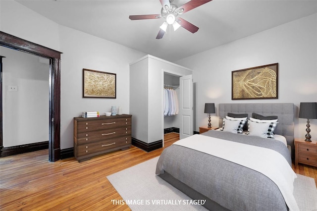 bedroom with a walk in closet, light hardwood / wood-style floors, a closet, and ceiling fan