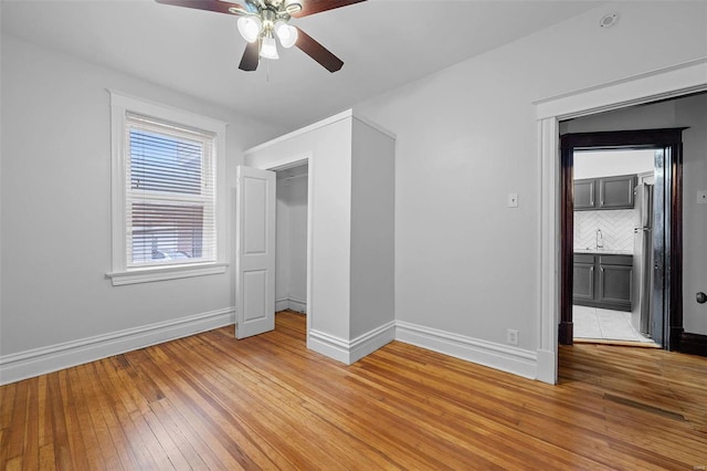 unfurnished bedroom with wood-type flooring, sink, ceiling fan, and stainless steel refrigerator