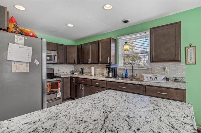 kitchen featuring pendant lighting, sink, dark brown cabinets, and stainless steel appliances