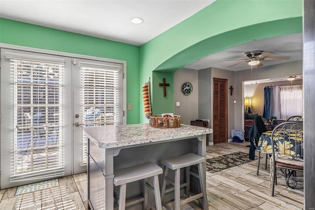 kitchen with a breakfast bar area, ceiling fan, and french doors