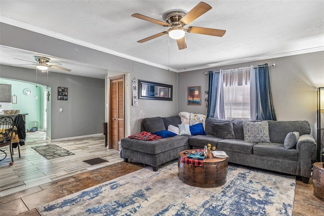 living room featuring ceiling fan, ornamental molding, and a textured ceiling