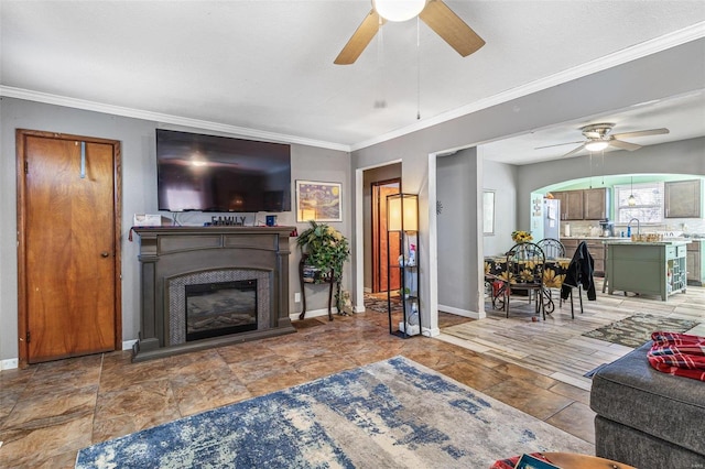 living room featuring ceiling fan, ornamental molding, and sink
