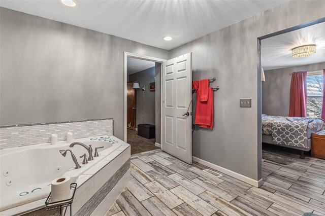 bathroom with a relaxing tiled tub and hardwood / wood-style flooring