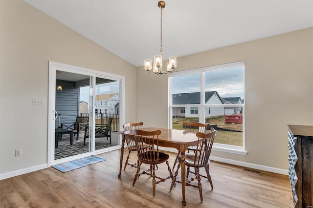 dining area featuring vaulted ceiling, an inviting chandelier, and light hardwood / wood-style floors