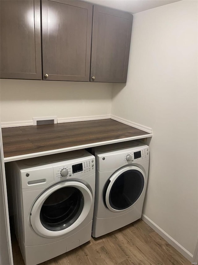 washroom featuring cabinets, hardwood / wood-style floors, and independent washer and dryer