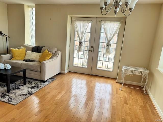 doorway to outside with an inviting chandelier, light wood-type flooring, and french doors