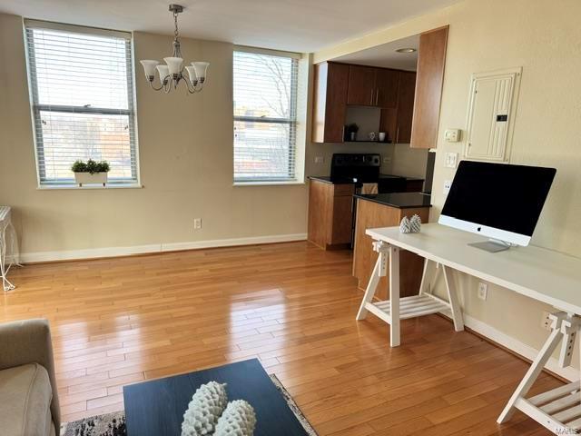 office featuring an inviting chandelier, light hardwood / wood-style flooring, electric panel, and plenty of natural light