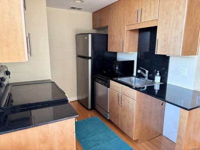 kitchen featuring stove, sink, stainless steel dishwasher, and light wood-type flooring