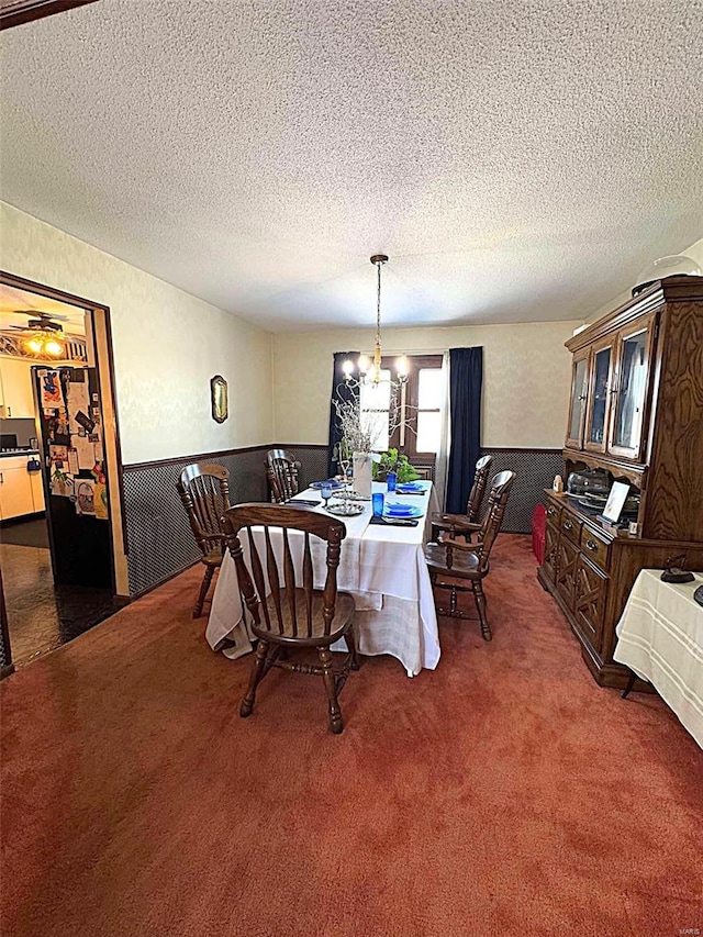 dining area featuring a chandelier, a textured ceiling, and dark carpet