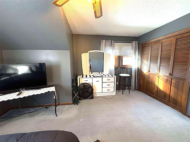 bedroom with light carpet, vaulted ceiling, a closet, and a textured ceiling