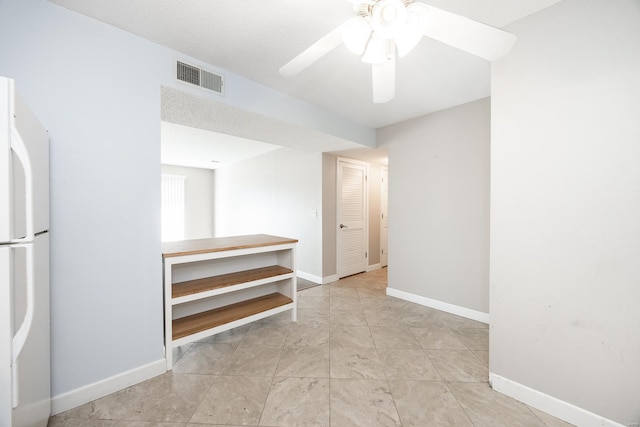 interior space with white fridge and ceiling fan