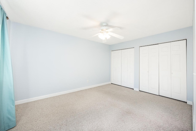 unfurnished bedroom featuring multiple closets, ceiling fan, and carpet flooring