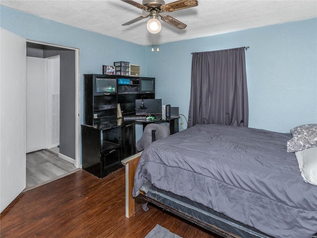 bedroom featuring dark hardwood / wood-style flooring, a textured ceiling, and ceiling fan