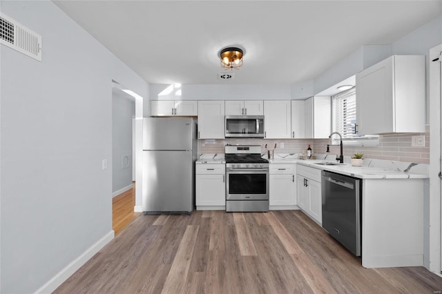 kitchen with white cabinetry, appliances with stainless steel finishes, sink, and backsplash