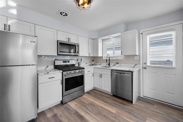 kitchen featuring sink, decorative backsplash, white cabinets, and appliances with stainless steel finishes