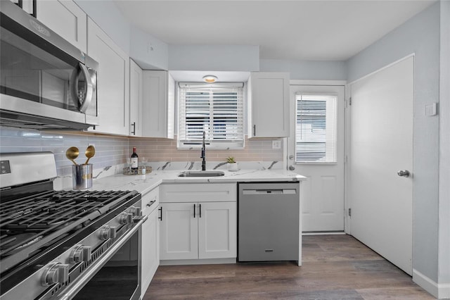 kitchen featuring sink, wood-type flooring, appliances with stainless steel finishes, light stone countertops, and white cabinets