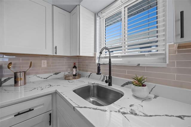 kitchen with white cabinetry, sink, and light stone counters