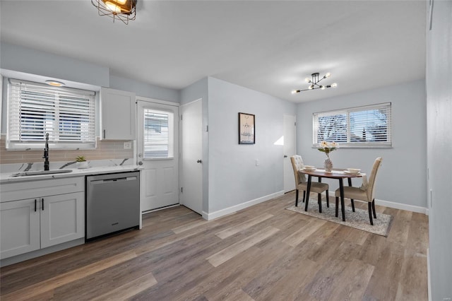 kitchen featuring sink, tasteful backsplash, light wood-type flooring, dishwasher, and white cabinets