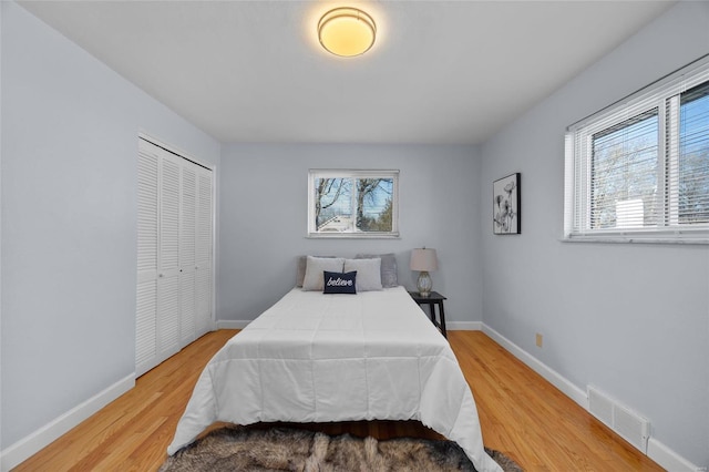 bedroom featuring hardwood / wood-style flooring, multiple windows, and a closet