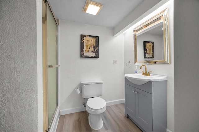 bathroom featuring wood-type flooring, toilet, an enclosed shower, and vanity