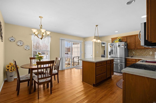 kitchen with a center island, hardwood / wood-style flooring, pendant lighting, stainless steel appliances, and backsplash