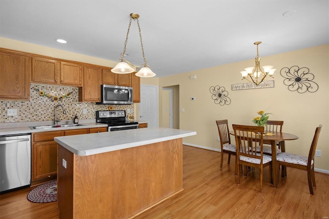 kitchen with sink, a center island, pendant lighting, stainless steel appliances, and backsplash