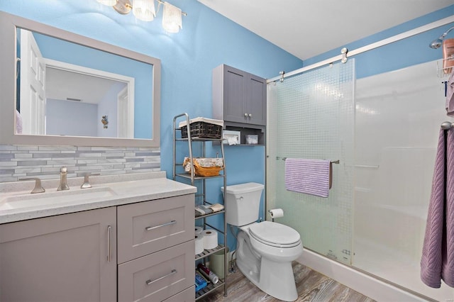 bathroom with toilet, hardwood / wood-style floors, backsplash, and a shower with shower door