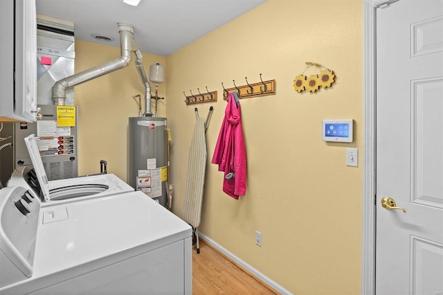 washroom with light hardwood / wood-style floors, washing machine and dryer, and water heater