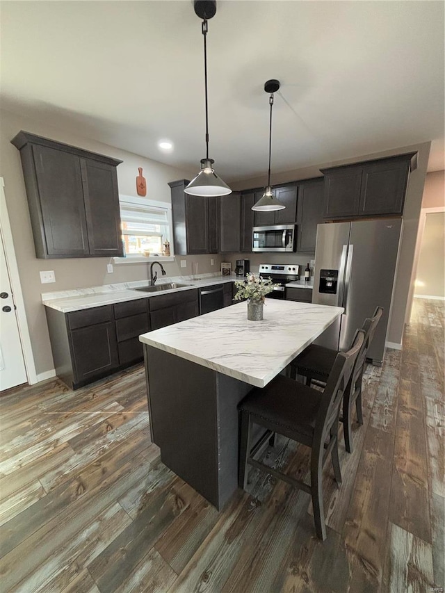 kitchen featuring sink, a center island, dark hardwood / wood-style floors, pendant lighting, and stainless steel appliances