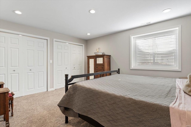 bedroom with two closets and carpet flooring