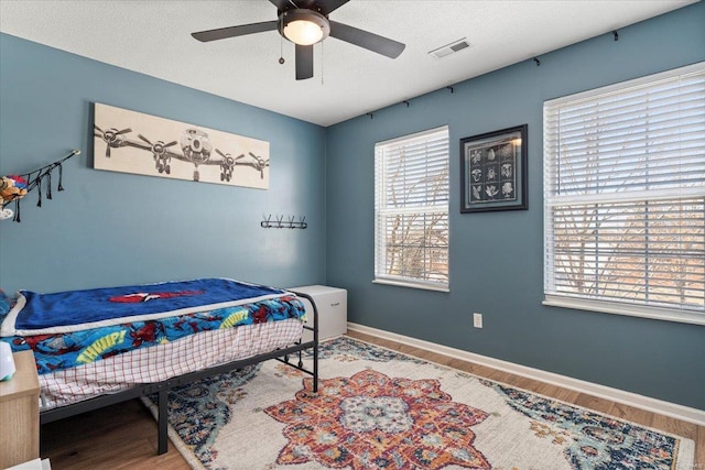 bedroom with hardwood / wood-style floors, a textured ceiling, and ceiling fan