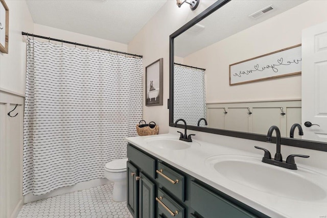 bathroom with tile patterned flooring, vanity, a textured ceiling, toilet, and walk in shower