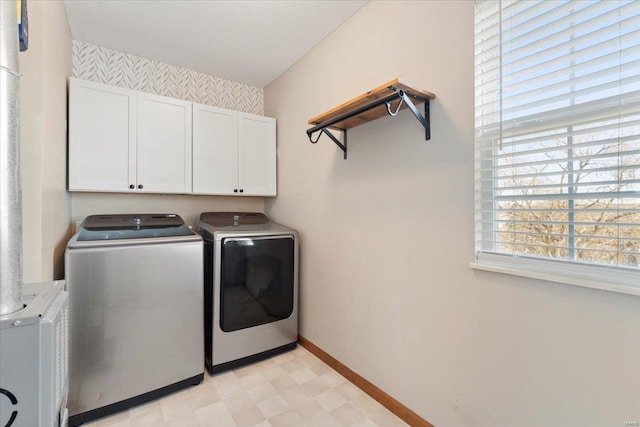 clothes washing area featuring cabinets and separate washer and dryer