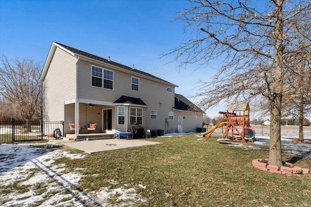 snow covered back of property featuring a playground, a patio, central AC, and a lawn