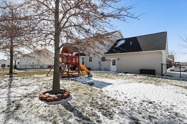 snow covered back of property with a playground