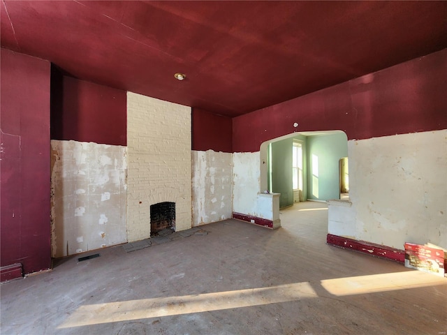 unfurnished room featuring concrete floors and a fireplace