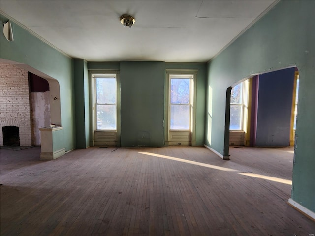 unfurnished living room with ornamental molding, hardwood / wood-style floors, and a brick fireplace