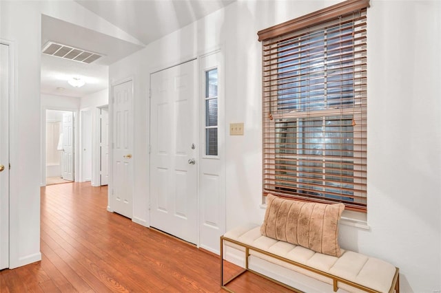 hallway featuring wood-type flooring and vaulted ceiling