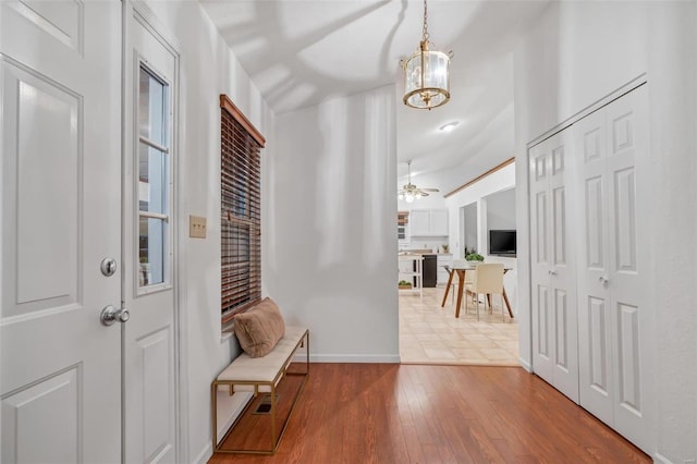 entryway featuring ceiling fan with notable chandelier and light hardwood / wood-style flooring