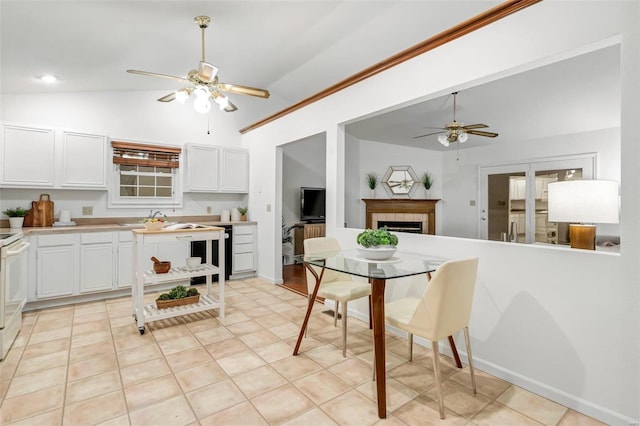 kitchen with white cabinets, vaulted ceiling, ceiling fan, and a fireplace