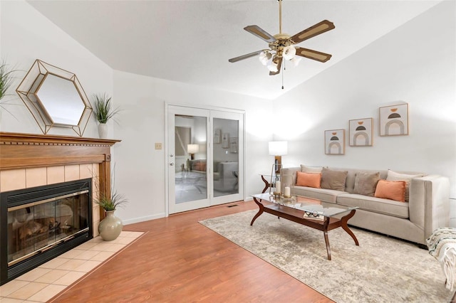 living room featuring a tiled fireplace, light hardwood / wood-style floors, and ceiling fan