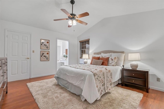 bedroom with ceiling fan, light hardwood / wood-style floors, connected bathroom, and lofted ceiling