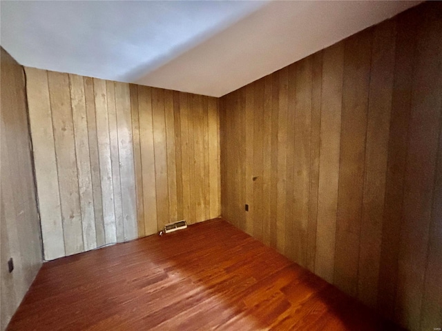 unfurnished room with hardwood / wood-style floors and wood walls