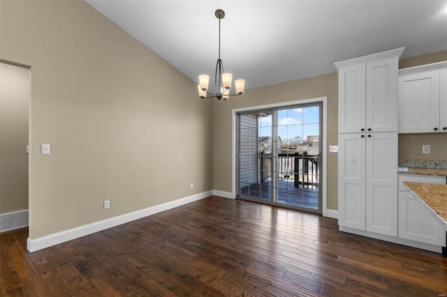 unfurnished dining area with lofted ceiling, dark hardwood / wood-style floors, and an inviting chandelier