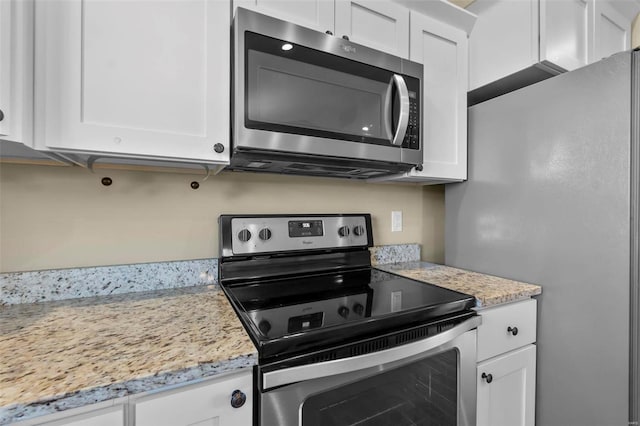 kitchen featuring stainless steel appliances, light stone countertops, and white cabinets