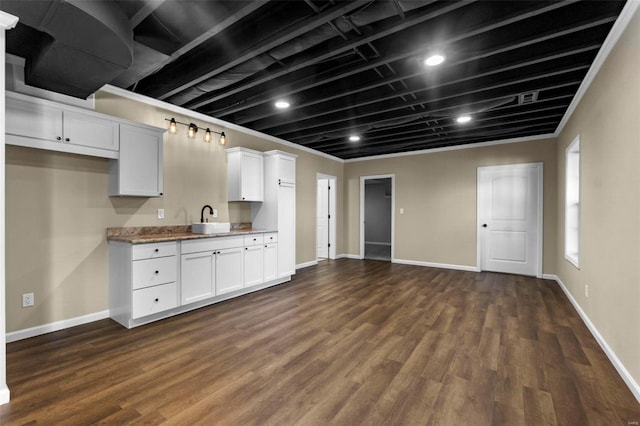 kitchen with white cabinetry, sink, dark wood-type flooring, and light stone counters