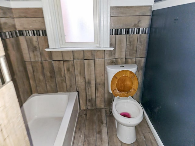 bathroom with wood-type flooring, a bath, and toilet