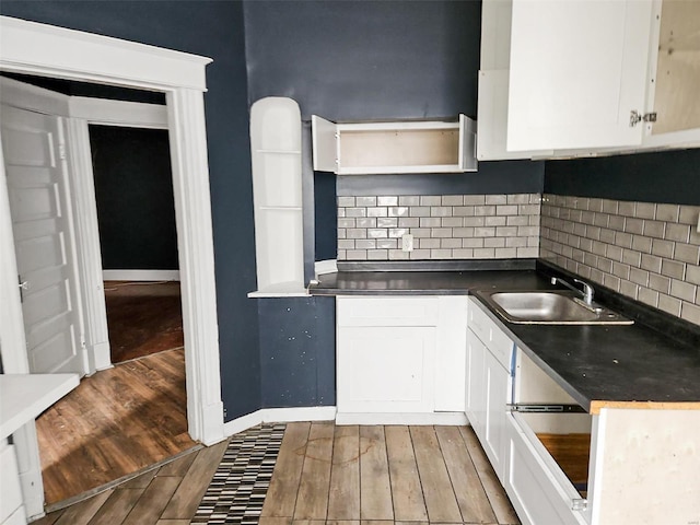 kitchen featuring wood-type flooring, sink, decorative backsplash, and white cabinets