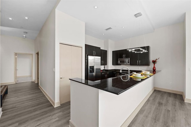 kitchen with sink, light hardwood / wood-style flooring, kitchen peninsula, and appliances with stainless steel finishes